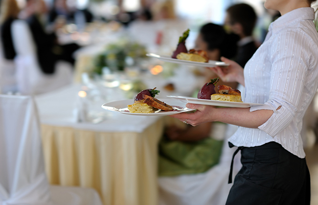 Waitress is carrying three plates with meat dish