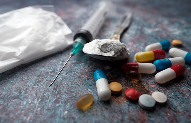 Drug syringe and cooked heroin on spoon, close up