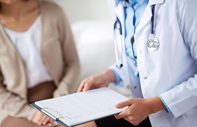 Female doctor holding application form while consulting patient