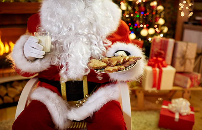 Christmas, holidays, food, drink and people concept -close up of Santa Claus with glass of milk and cookies