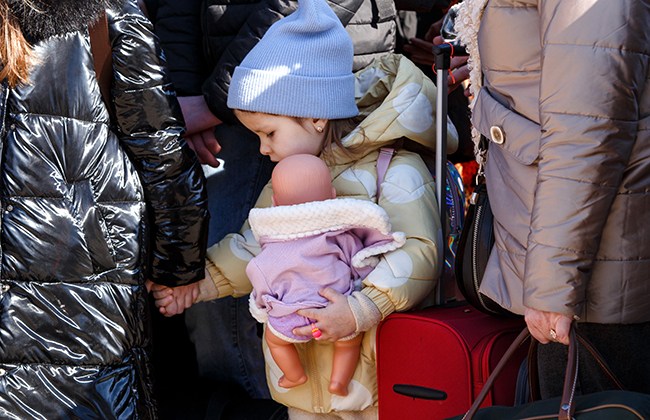 UZHHOROD, UKRAINE - FEBRUARY 27, 2022 - A little girl holding a woman's hand clutches a doll at the Uzhhorod-Vysne Nemecke checkpoint on the Ukraine-Slovakia border, Zakarpattia Region, western Ukraine. 